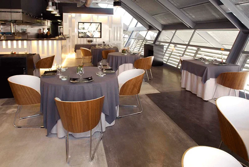 Restaurante de estilo moderno con mesas redondas y sillas de madera y metal decorado por PortobelloStreet 